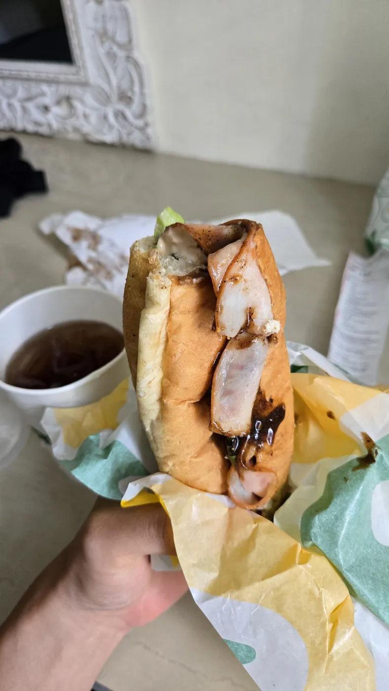 한 손에 든 서브웨이 샌드위치와 종이컵에 담긴 아이스티