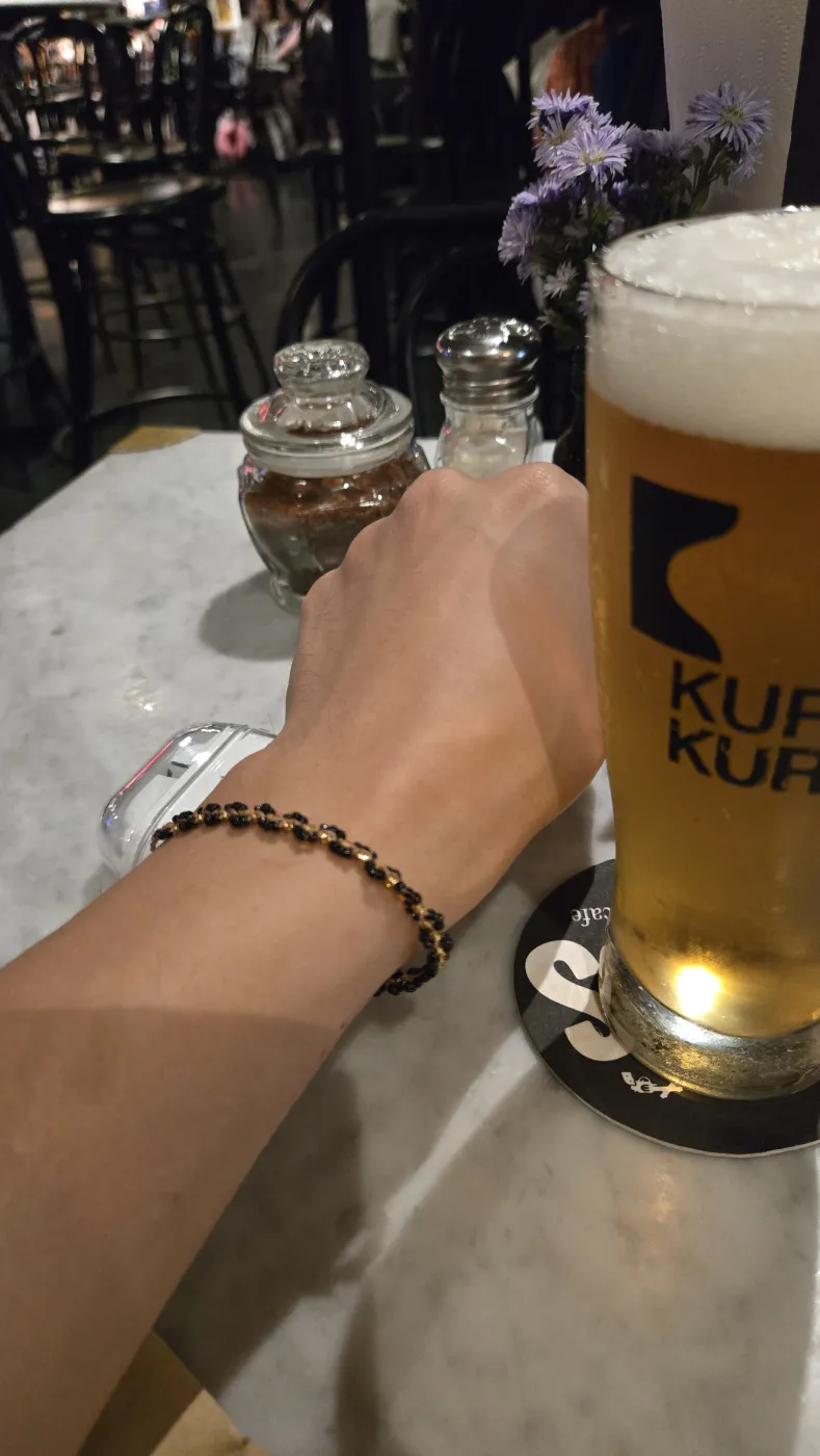 손목에 찬 구슬 팔찌와 애플워치, 옆에 KURA KURA 생맥주 한 잔